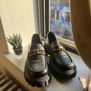 Chunky black loafers with gold chain detail
